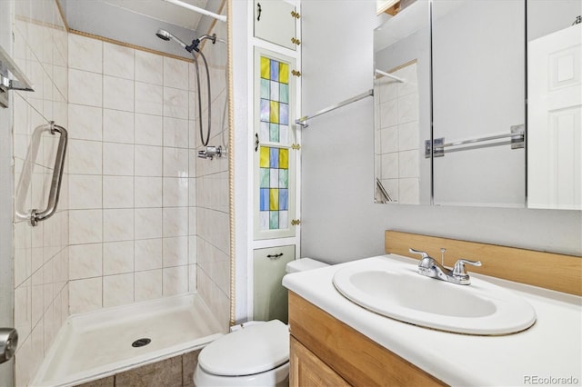 bathroom with toilet, vanity, and a tile shower