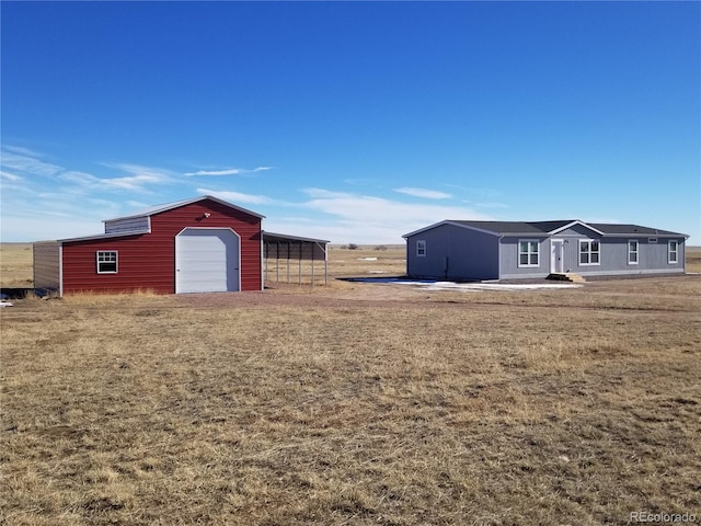 view of yard featuring a carport, a garage, and an outdoor structure