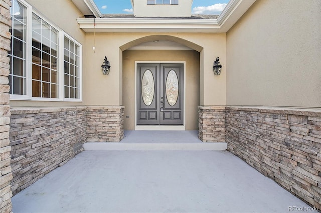 entrance to property featuring stone siding and stucco siding