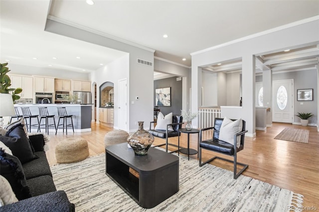 living area with arched walkways, recessed lighting, visible vents, light wood-style flooring, and baseboards