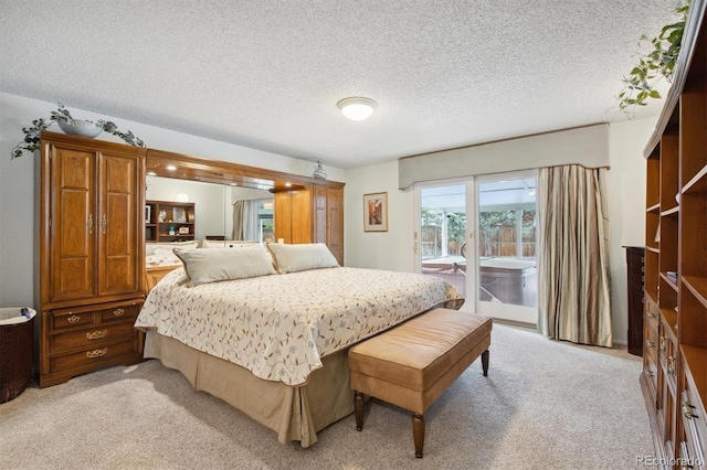 bedroom featuring access to exterior, light carpet, and a textured ceiling