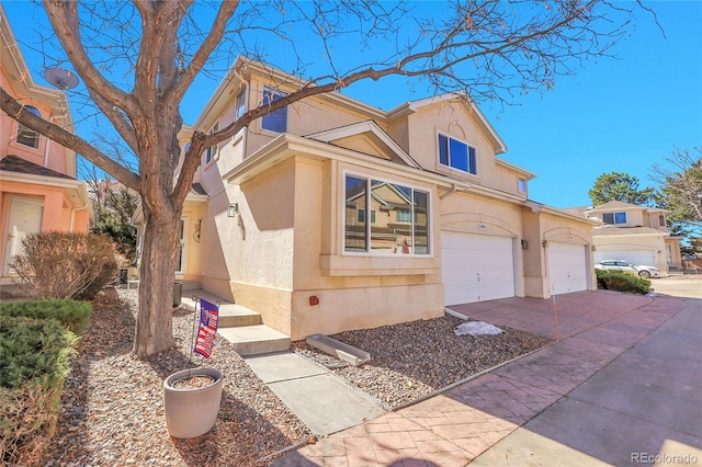 townhome / multi-family property with driveway, an attached garage, and stucco siding