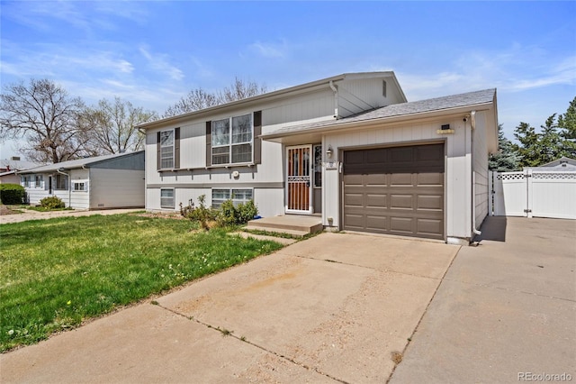 tri-level home with fence, an attached garage, driveway, and a front yard