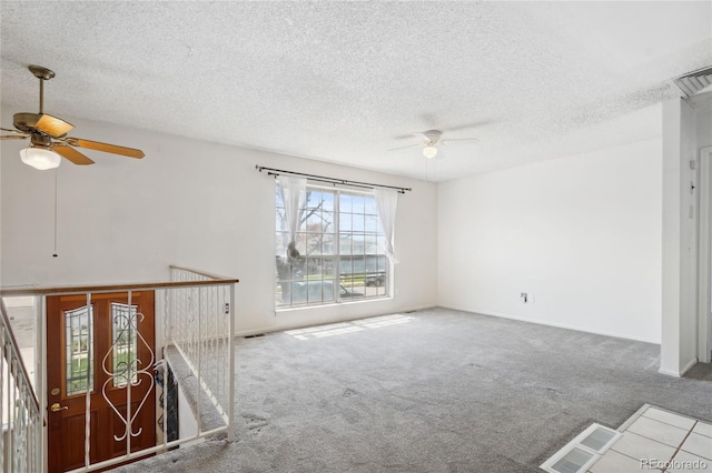 carpeted spare room with a ceiling fan, a textured ceiling, and visible vents