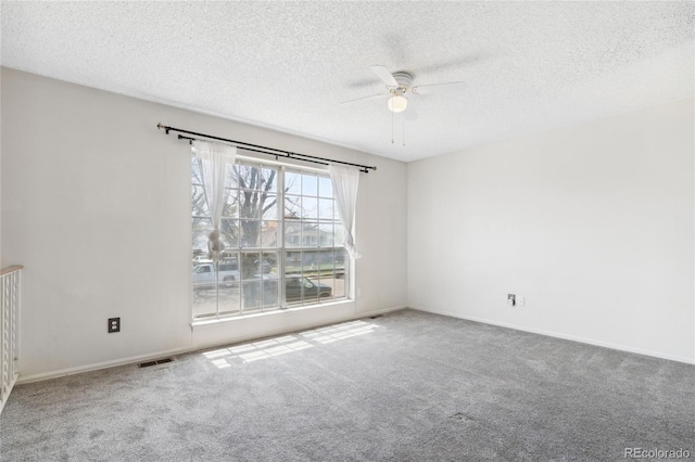 carpeted spare room featuring baseboards, ceiling fan, a textured ceiling, and visible vents