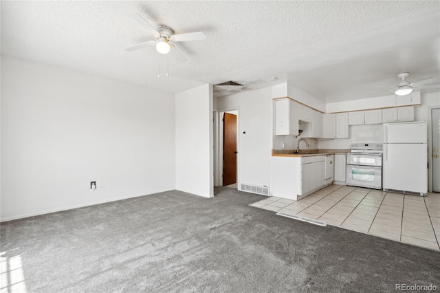 kitchen with a ceiling fan, a textured ceiling, light colored carpet, white appliances, and white cabinetry
