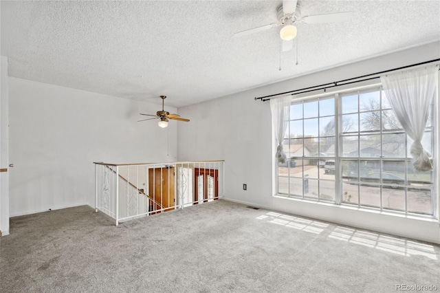 carpeted spare room featuring a ceiling fan, a textured ceiling, and visible vents