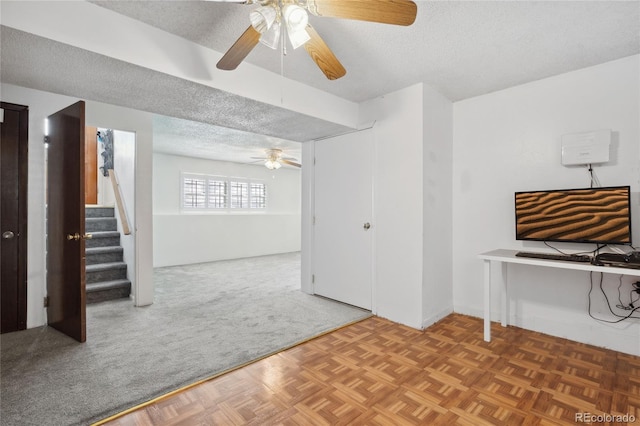 basement with a ceiling fan, a textured ceiling, carpet flooring, and stairway