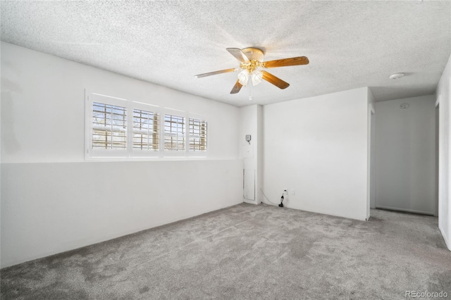 unfurnished room with carpet flooring, a ceiling fan, and a textured ceiling