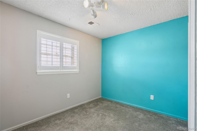carpeted spare room with baseboards, a textured ceiling, and visible vents