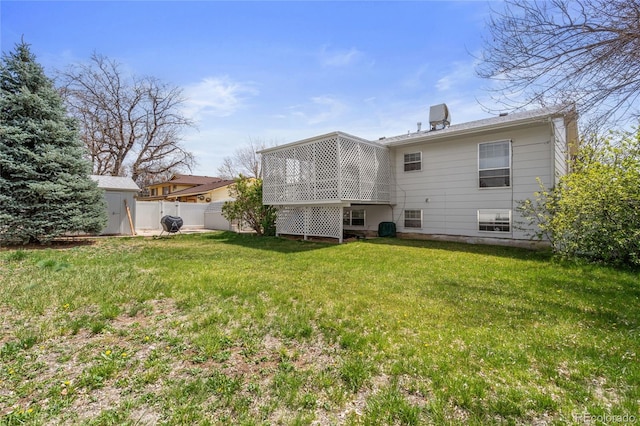 rear view of house with a lawn and fence