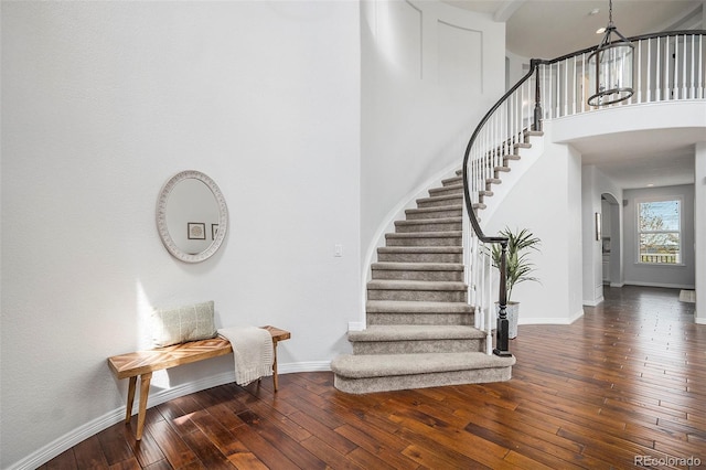 2749 Pemberly Ave, Highlands Ranch, CO 80126 - staircase featuring wood-type flooring, baseboards, arched walkways, and a towering ceiling