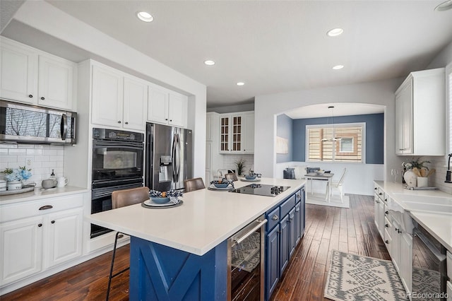 2749 Pemberly Ave, Highlands Ranch, CO 80126 - kitchen with black appliances, beverage cooler, blue cabinetry, white cabinetry, and decorative backsplash