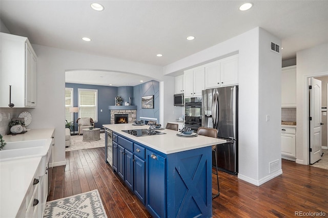 2749 Pemberly Ave, Highlands Ranch, CO 80126 - kitchen with black appliances, blue cabinets, arched walkways, a center island, and white cabinetry