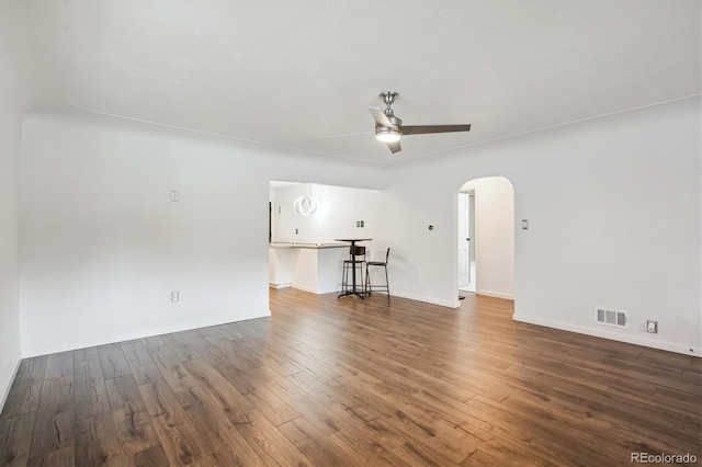 2989 S Corona St, Englewood, CO 80113 - unfurnished living room featuring arched walkways, wood finished floors, ceiling fan, and baseboards