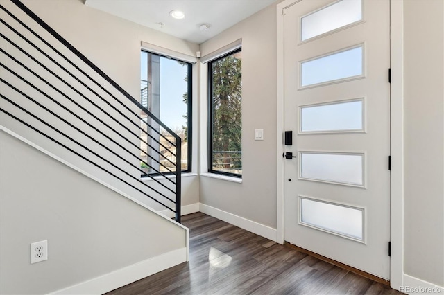 foyer featuring a healthy amount of sunlight, stairs, baseboards, and dark wood-type flooring