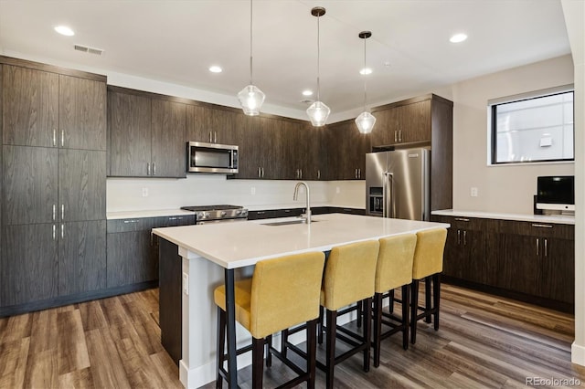 kitchen with a sink, visible vents, light countertops, appliances with stainless steel finishes, and dark wood finished floors