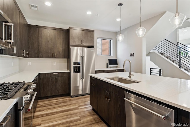 kitchen with light wood finished floors, light countertops, visible vents, appliances with stainless steel finishes, and a sink