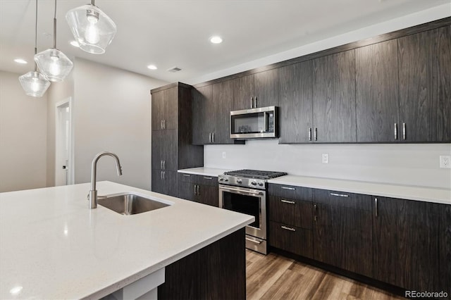 kitchen with light countertops, visible vents, appliances with stainless steel finishes, light wood-style floors, and a sink