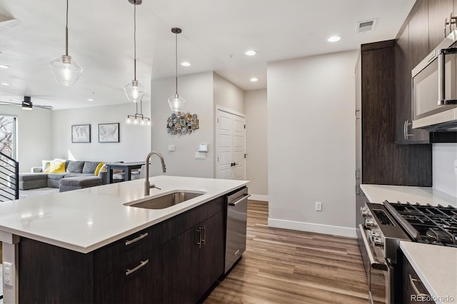 kitchen with visible vents, appliances with stainless steel finishes, wood finished floors, light countertops, and a sink