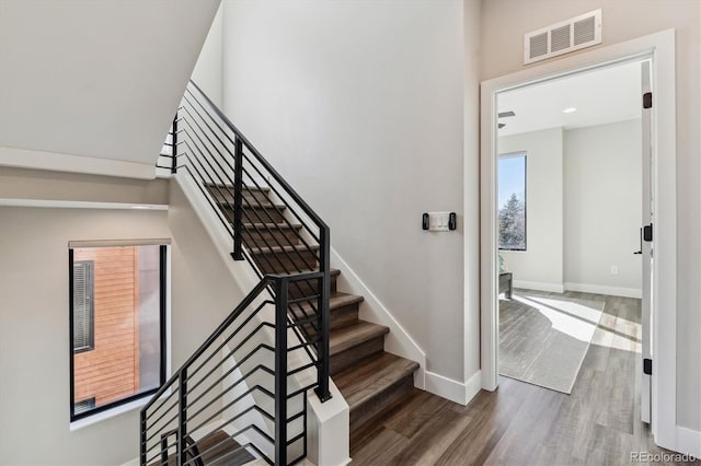 staircase featuring wood finished floors, visible vents, and baseboards