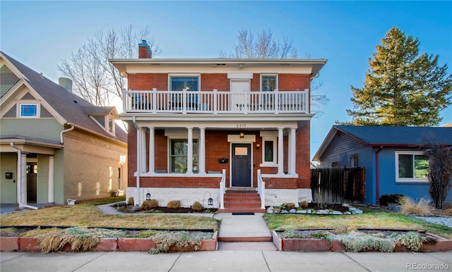 view of front facade featuring a balcony, brick siding, fence, a front lawn, and a chimney