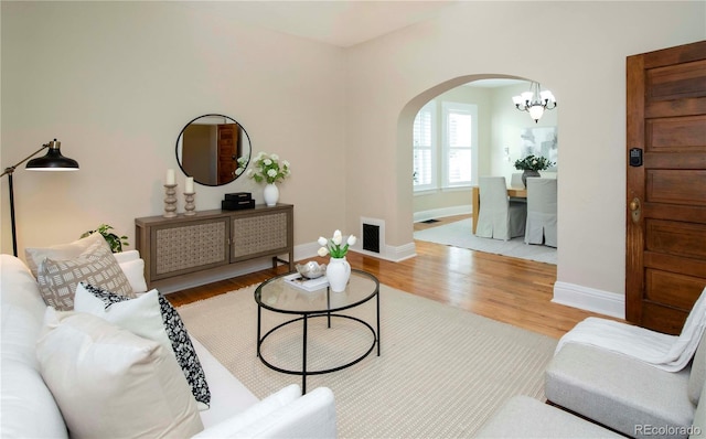 living area with arched walkways, visible vents, baseboards, and wood finished floors