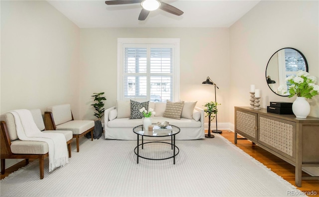 living area featuring ceiling fan, baseboards, and wood finished floors