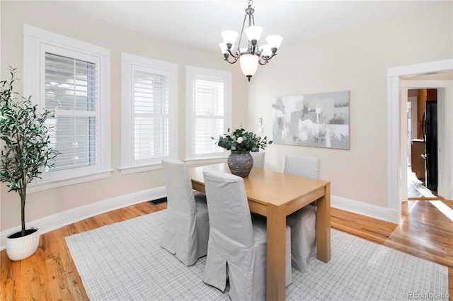 dining space with light wood-style flooring, baseboards, and an inviting chandelier