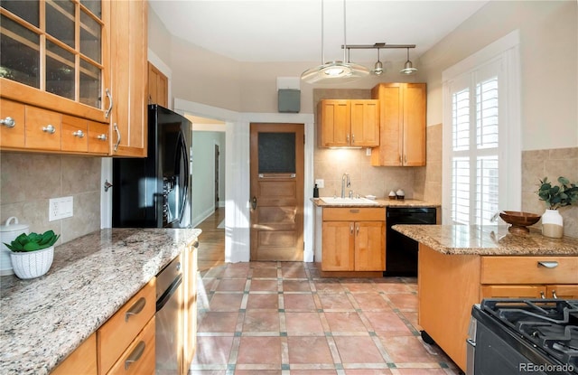 kitchen featuring light stone counters, glass insert cabinets, a sink, black appliances, and backsplash