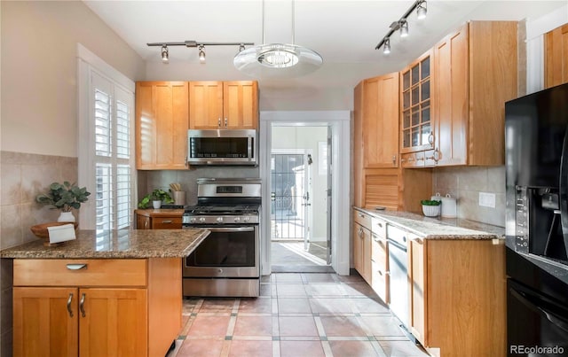 kitchen featuring glass insert cabinets, tasteful backsplash, black appliances, and light stone countertops