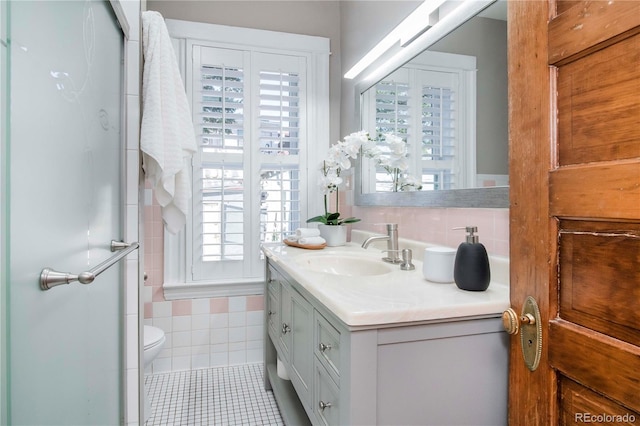 full bath featuring tile patterned flooring, toilet, vanity, tile walls, and a stall shower