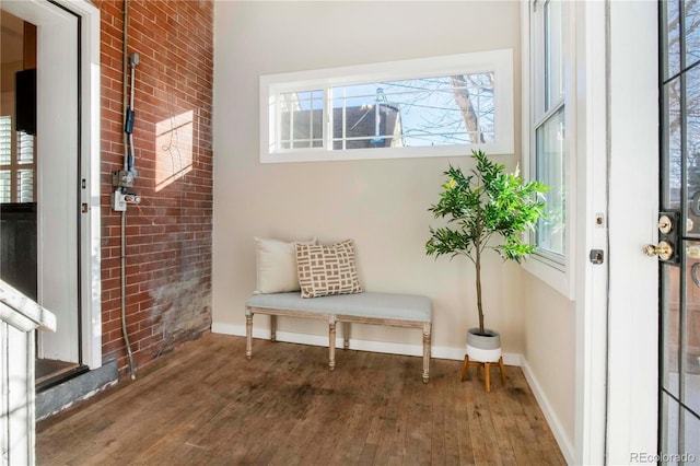 mudroom with hardwood / wood-style flooring, brick wall, and baseboards