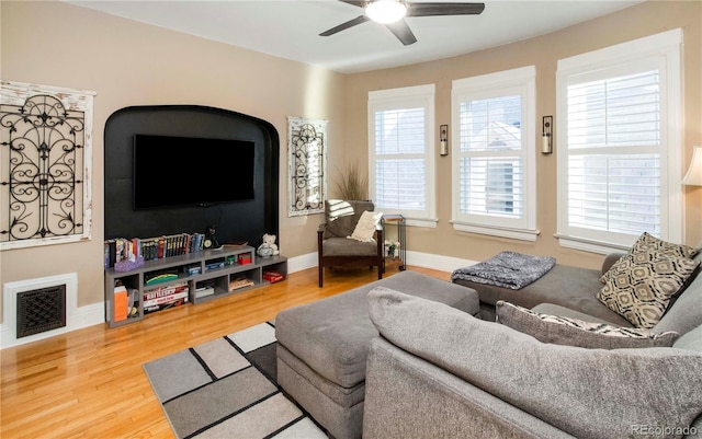 living room featuring visible vents, ceiling fan, baseboards, and wood finished floors