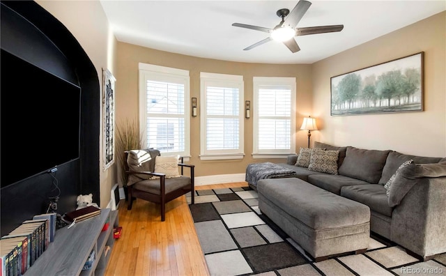 living room featuring baseboards, light wood-style flooring, and a ceiling fan