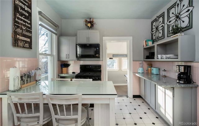 kitchen with black appliances, decorative backsplash, a wealth of natural light, and light floors