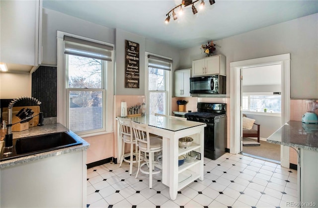 kitchen featuring light floors, black appliances, white cabinetry, open shelves, and a sink