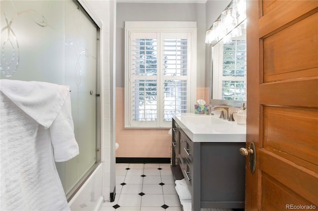 full bathroom with tile patterned flooring, plenty of natural light, tile walls, and vanity