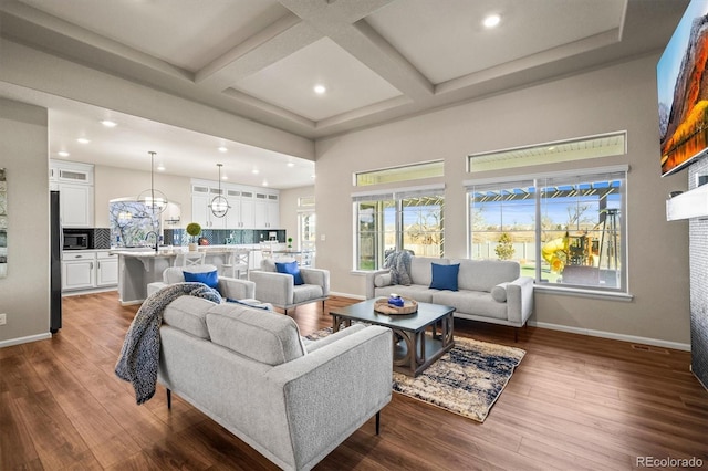 living area featuring dark wood-style floors, a high ceiling, coffered ceiling, beamed ceiling, and baseboards