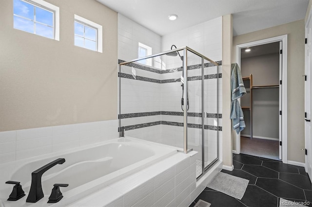 full bath featuring a stall shower, baseboards, a garden tub, tile patterned flooring, and a spacious closet