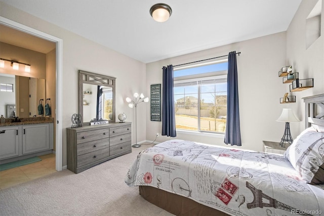 bedroom with light colored carpet, baseboards, and ensuite bathroom