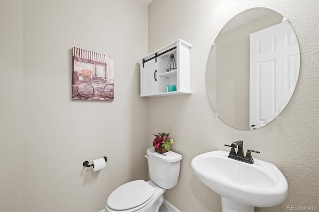 bathroom with a sink, toilet, and baseboards