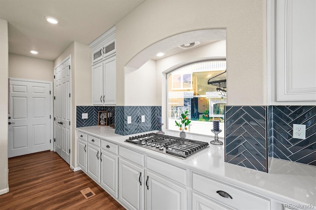 kitchen with stainless steel gas cooktop, dark wood-style flooring, white cabinets, decorative backsplash, and glass insert cabinets