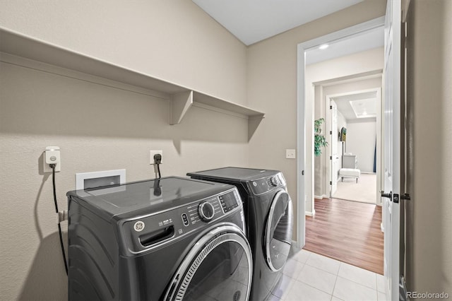 washroom featuring light tile patterned floors, laundry area, baseboards, and washer and dryer