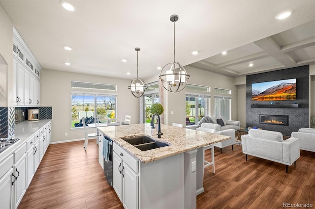 kitchen with dark wood finished floors, a large fireplace, white cabinetry, and a sink