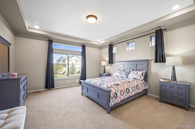 bedroom with a raised ceiling, recessed lighting, light colored carpet, and baseboards