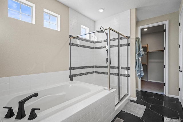 full bath featuring tile patterned flooring, a walk in closet, baseboards, a stall shower, and a bath