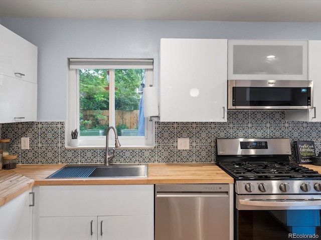 10109 W 68th Ave, Arvada, CO 80004 - kitchen with stainless steel appliances, wood counters, white cabinetry, a sink, and decorative backsplash