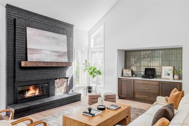 10953 E Crestline Ave, Englewood, CO 80111 - living room featuring light wood-type flooring, a fireplace, and a towering ceiling