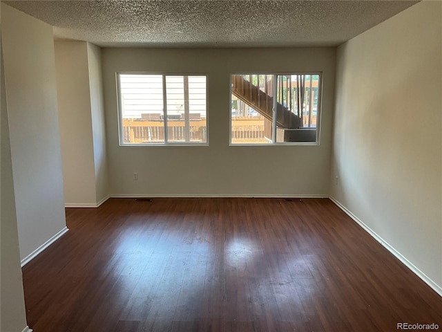 empty room featuring a textured ceiling and dark hardwood / wood-style flooring